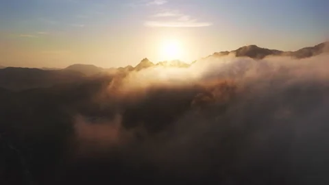 Flying through amazing sunny cloudscape toward golden sun rising over mountains 스톡 동영상 162291788