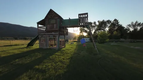 Flying through a backyard playground at sunset in a rural valley, slow motion Видео 248162255