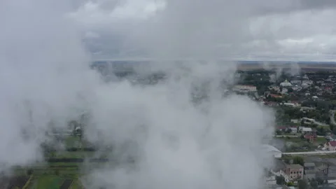 Flying through a cloud of smoke over a view of a picturesque green town. 4k Stock Footage 191202095
