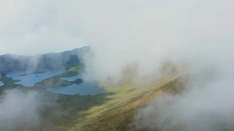 Flying through the cloud on the top of volcano. Green slopes and lakes of Stock Footage 119600666