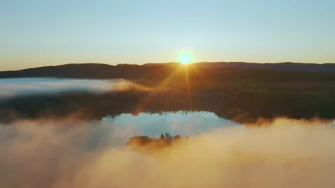 Flying through the clouds above lake surrounded by forest and mountain range Stock Footage 141033998