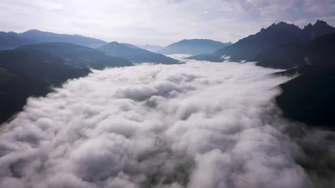 Flying through the clouds above mountain tops. High peaks wonderful morning Stock Footage 169369636