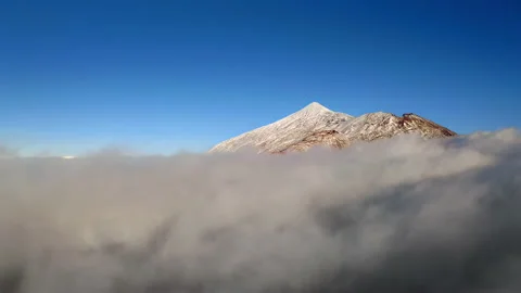 Flying through clouds between snow-capped mountains. Mount Teide in the snow. Stock Footage 146842715