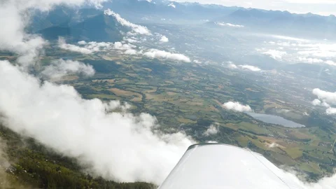 Flying through clouds in sky, aircraft wing. Above fields, mountains, cliff Stock Footage 125738185