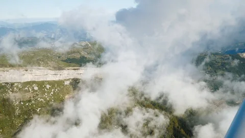 Flying through clouds in sky on aircraft, aerial view. Above mountains, cliff. Video stock 125738225