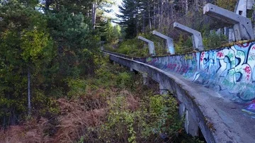 Flying through forests of Mount Trebevic over former Olympic bobsleigh track Stock Footage 85948619