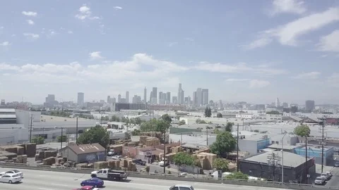 Flying "through" a freeway to reveal LA City Skyline in an industrial part of LA 動画素材 82285844