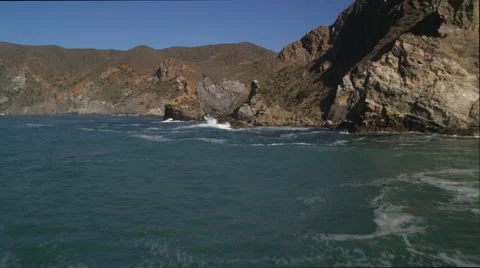 Flying through a gap between a sea stack and the shore on the Catalina coast, Stock Footage 59107178