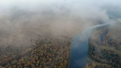Flying through a haze of clouds to a stunning autumn landscape with a winding Stock Footage 125731189