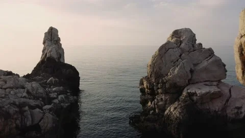 Flying through large rock formations on coast towards horizon Video stock 168772747