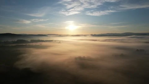 Flying through low fog towards bright sun over mountains. Stock Footage 338300190