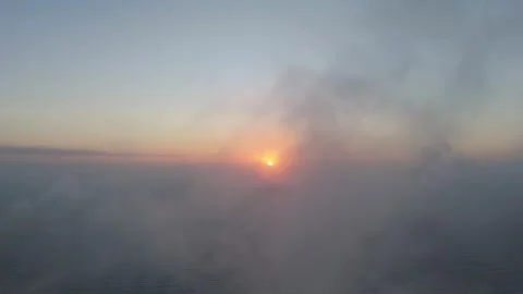 Flying through misty clouds at sunrise, the camera reveals the ocean as the.. Video stock 286309558