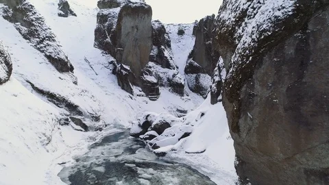 Flying through a snow covered canyon with river below: pristine landscape Video stock 88256529