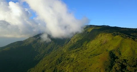 Flying to the top of the mountain under clear blue sky in front of clouds Stock Footage 108469679