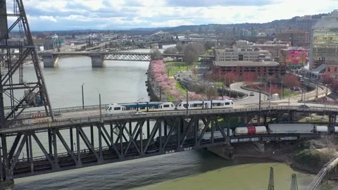 Flying toward cherry blossom trees as train passes over bridge in Portland. Stock Footage 172339653