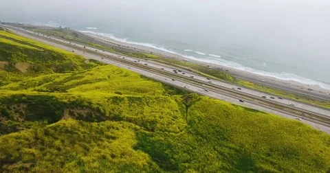 Flying toward ocean over flower covered mountains, highway 101 Stock Footage 74607203