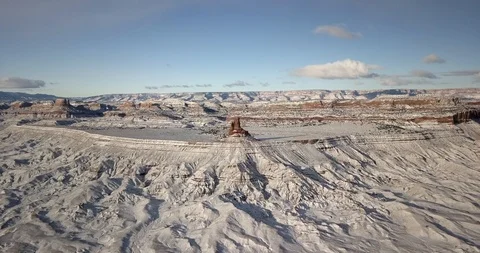 Flying toward red rock formation in a vast white expanse of desert snow Video stock 106482978