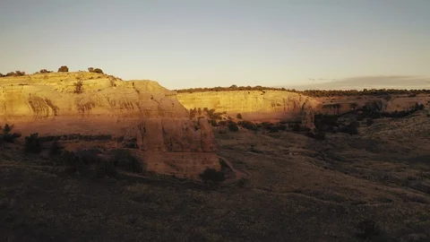 Flying toward red sandstone cliffs at sunset with golden light Stock Footage 127471597