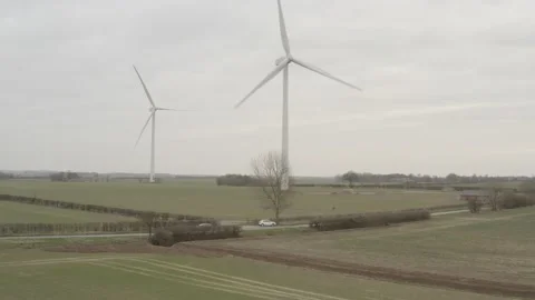 Flying towards 2 wind turbines over a tree and road. 4K D-Log 動画素材 149978688