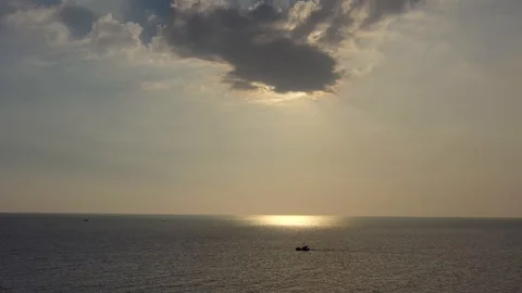 Flying towards lonely boat in ocean against sunset sun is hiding behind cloud Stock Footage 124106926