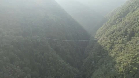 Flying towards mountain suspension bridge with lens flare in camera Stock Footage 282980014