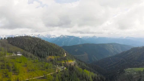 Flying towards snowy mountain over green hills, grass, forest. Austrian Alps. Stock Footage 95117480