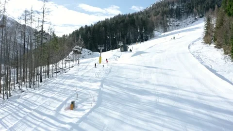 Flying towards start at empty snow-covered ski slope bordered by tall pine trees Stock Footage 285900437