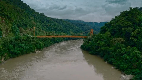 Flying towards suspension bridge in Amazon Rainforest above river 스톡 동영상 115827500