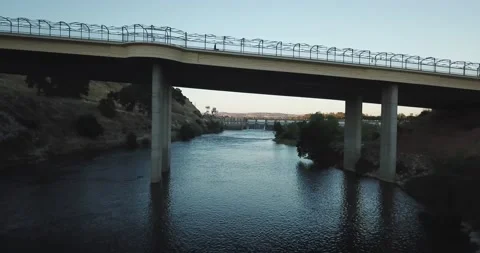 Flying under bridge and over dam at dusk Stock Footage 134913188