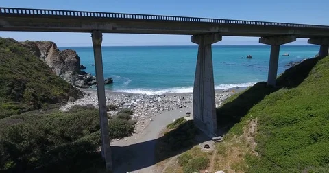 Flying under a bridge to the beach at Big Sur, California Stock Footage 76340406