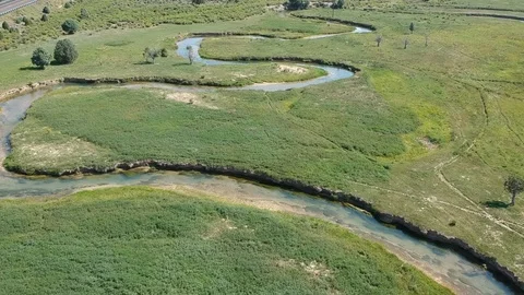 Flying upwards - zigzagging river and green nature Stock Footage 107878042