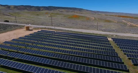 Flying view over solar panel farm away from fields of flowers Stock Footage 104812385