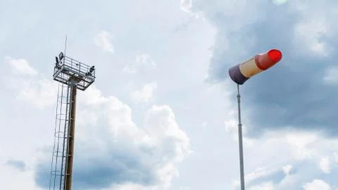 Flying windsock wind vane with red, white and blue lines on dramatic sky back Stock Photos