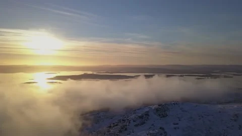 Flying on a winter day in the sun among low clouds over the mountain Stock Footage 143552293