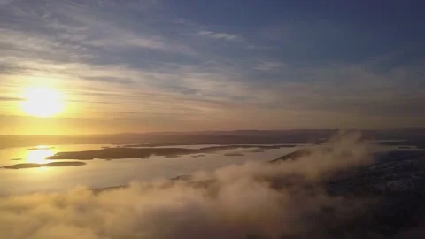Flying on a winter day in the sun among low clouds over the mountain Stock Footage 143680972