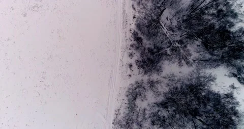 Flying on the winter road between the forest and the field and the village Stock Footage 147691561