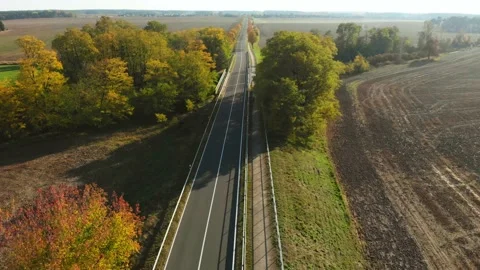 Flyover dolly in of road with car, trees and fields during day Stock Footage 134826757