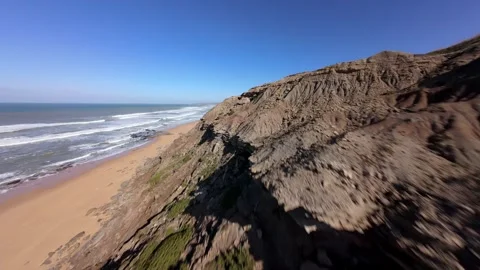Flyover of dramatic coastal landscape with textured cliffs and beach Video stock 346077544