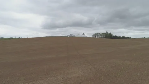 Flyover an Empty Farm Field Towards a Large Barn Video stock 210220979