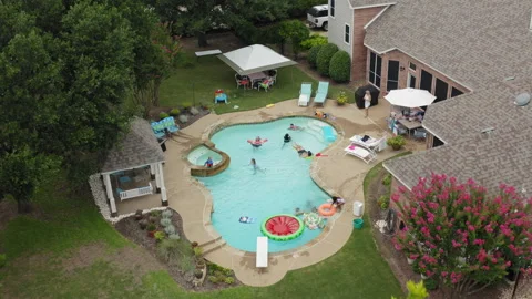 Flyover pool party revealed from behind tree in beautiful Texas residential yard Stock Footage 248078837