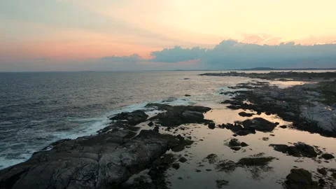 A flyover of sunset lit tidal pools near Peggy's Cove Stock Footage 214423855