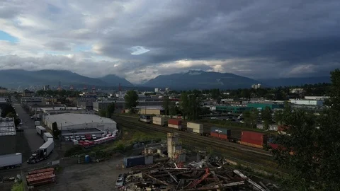 Flyover urban trainyard with dramatic mountains and clouds Видео 111236869