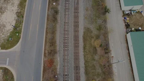 Flyover View of Train Tracks beside a road with Cars Passing by Stock Footage 325808211