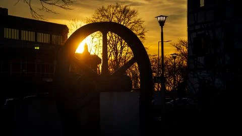 The flywheel of an old steam engine in the rays of the setting sun next to .. Stock Photos