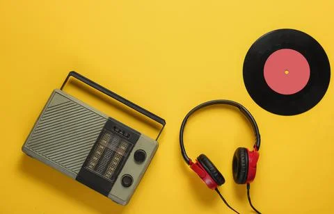FM radio receiver, retro style wired headphones, vinyl record on yellow backg Stock Photos