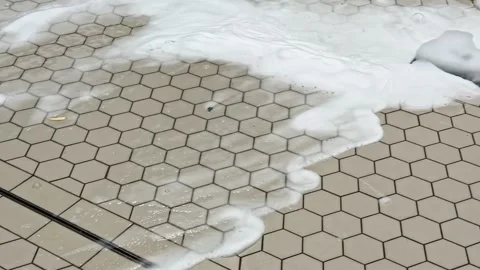 Foam and water being pushed across a tiled floor with a squeegee during an Stock Footage 326282191
