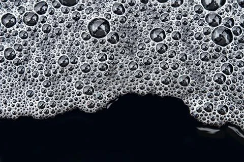 Foam with bubbles pattern on dark water surface after heavy rain Foto stock