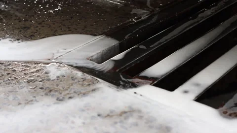 Foam from the car wash flows into the drain Stock Footage 212456650