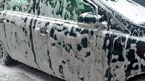 Foam car wash process with thick soap covering entire vehicle during cleaning Stock Footage 310955824