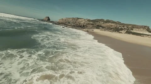 Foam crashes over rocks and sandy shore Stock Footage 341822248